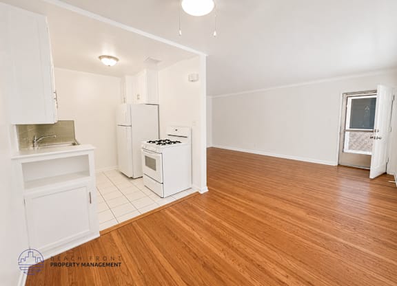A kitchen with white appliances and wooden floors.