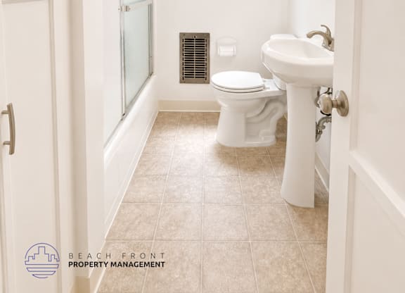 A white bathroom with a toilet, sink, and shower.