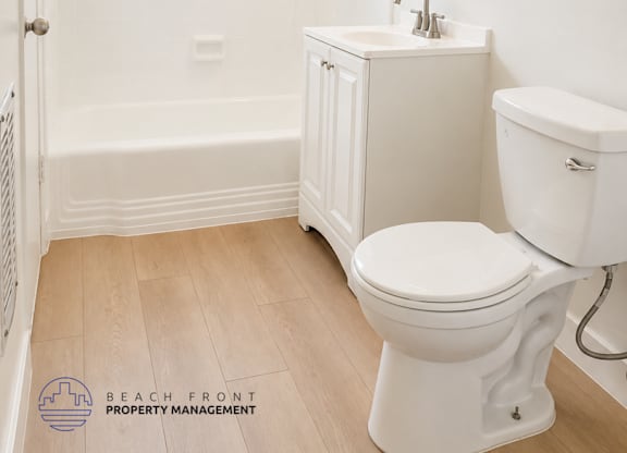 A white toilet in a bathroom with a wooden floor.