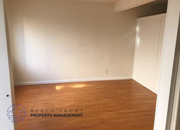 an empty room with wood flooring and white walls