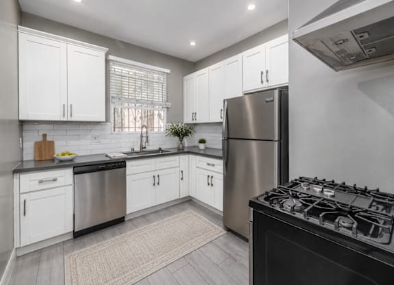 A modern kitchen with white cabinets and stainless steel appliances.