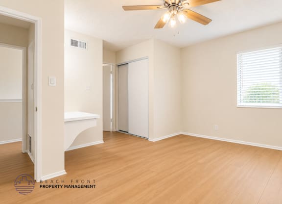 A spacious room with a ceiling fan and a window with blinds.