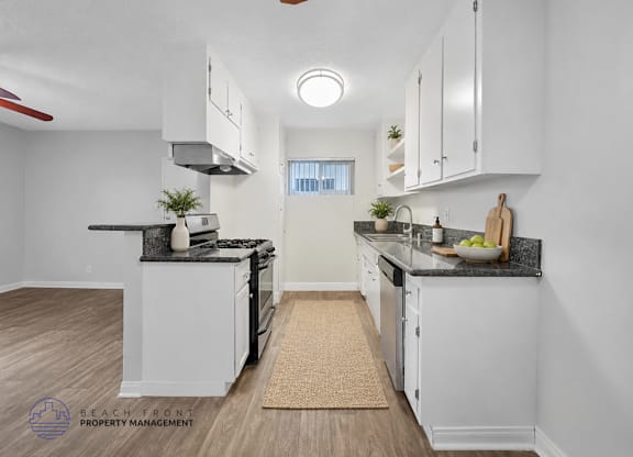 A kitchen with white cabinets and a black countertop.