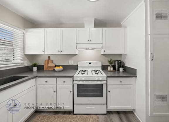 A kitchen with white cabinets and a stove top oven.