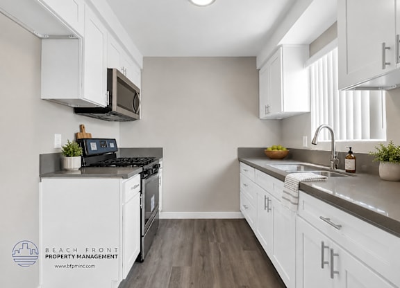 A kitchen with white cabinets and a black stove top.