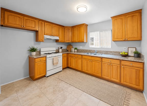 A kitchen with wooden cabinets and a white stove top oven.