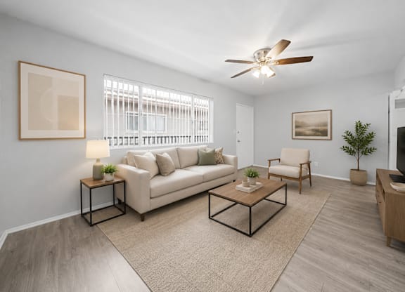 A living room with a beige couch, a coffee table, and a ceiling fan.