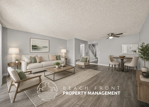 A living room with a staircase in the background and a logo for Beach Front Property Management.