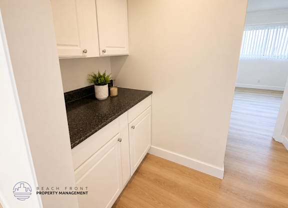 A kitchen with white cabinets and a black countertop.