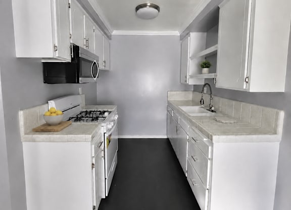 A small white kitchen with a microwave, oven, and sink.