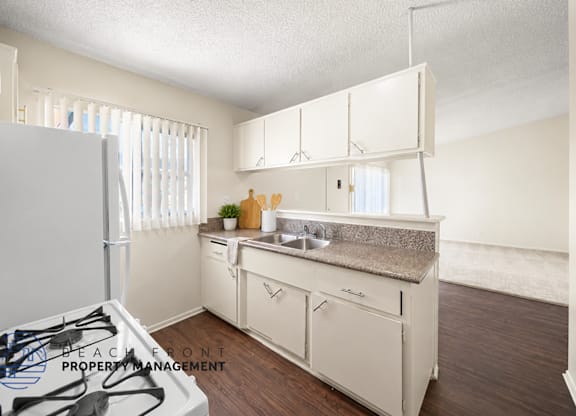 A kitchen with white cabinets and a countertop with a sink.