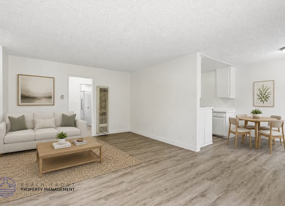 A living room with a white couch, a coffee table, and a dining table with chairs.