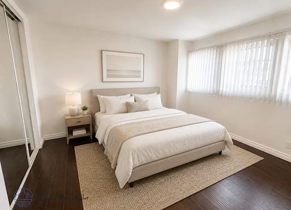 A bedroom with a large bed and a nightstand with a lamp.