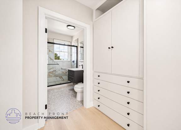 A white bathroom with a toilet, sink, and a large mirror.