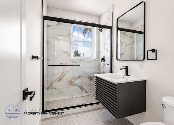 A bathroom with a marble sink and a glass shower door.