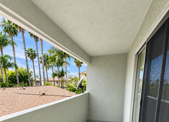 A balcony with a view of a roof and trees.