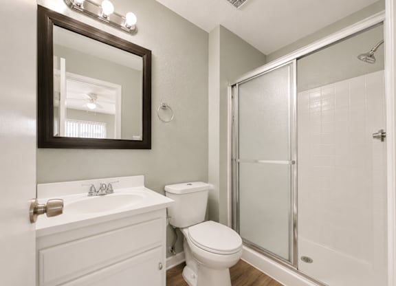A white bathroom with a toilet, sink, and shower.