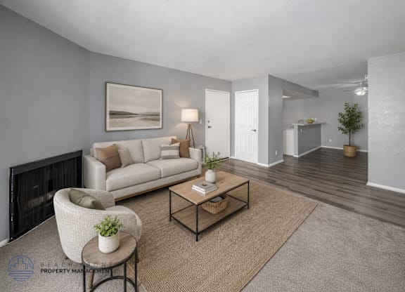 A living room with a white couch, a chair, a coffee table, and a painting on the wall.