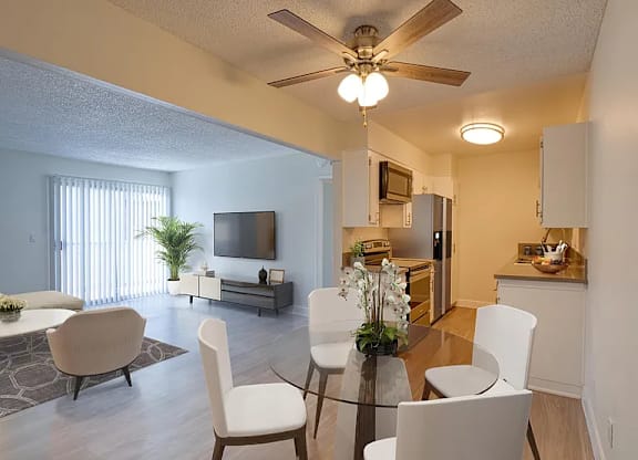 A living room with a television, a dining table and chairs, and a kitchen area.
