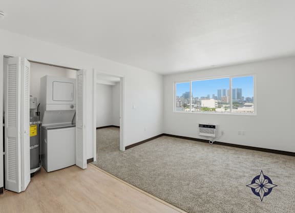 A room with a window overlooking a cityscape, a carpet with a star design, and a white wall.
