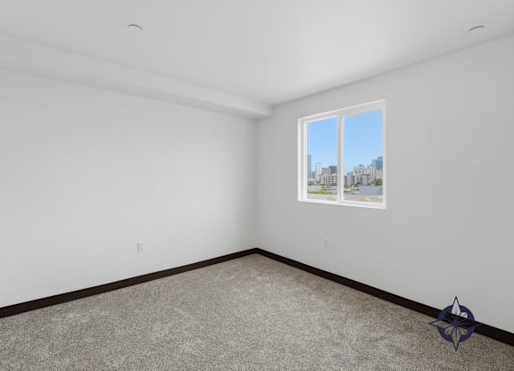 A room with a carpeted floor and a window showing a cityscape outside.