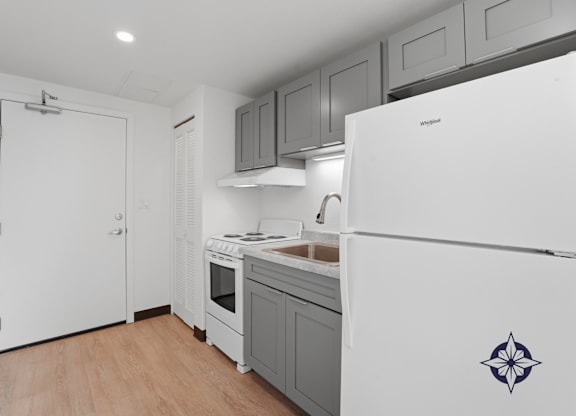 A modern kitchen with a white fridge and a wooden floor.