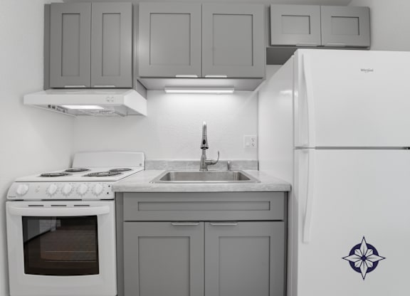 A kitchen with a white refrigerator, stove, and cabinets.
