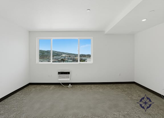 A room with a large window and a carpeted floor.
