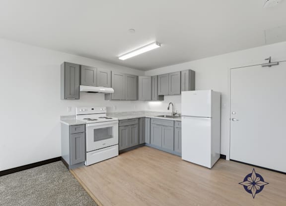 A modern kitchen with white appliances and grey cabinets.