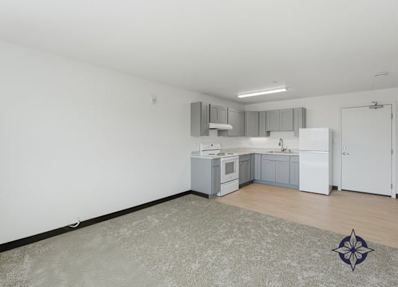 A kitchen with white cabinets and a white fridge is shown.