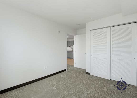 A room with a carpeted floor and a white wall with a door and a window.