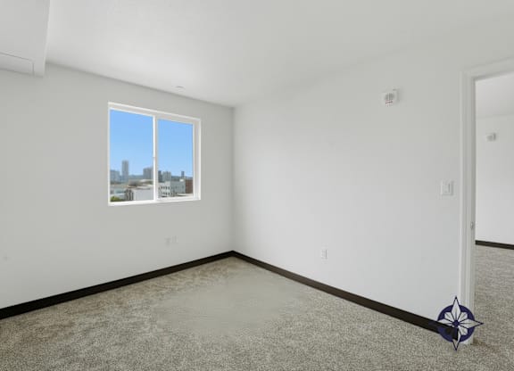 A room with a carpeted floor, a window, and a door.