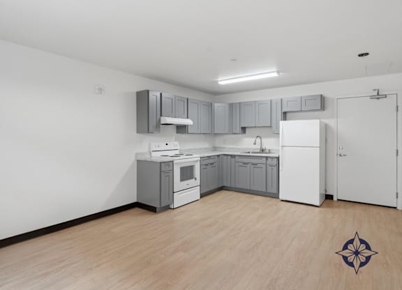 A kitchen with white appliances and wooden floors.