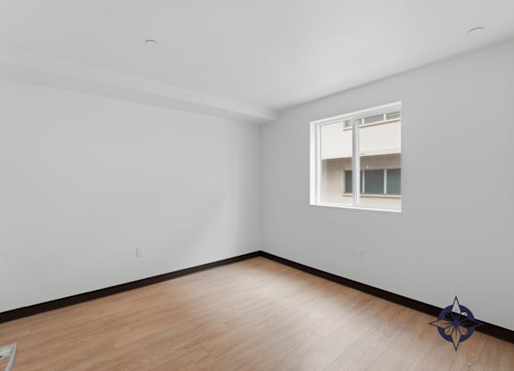 A room with a window and a wooden floor.