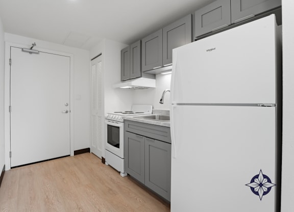 A kitchen with a white fridge and a white door.