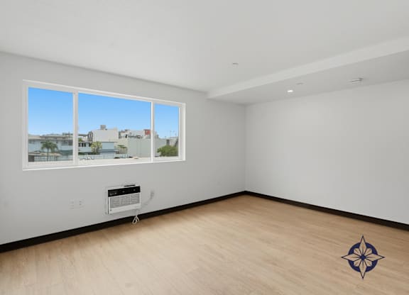 A room with a window overlooking a cityscape and a wooden floor with a compass design.