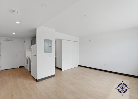 A room with a white wall and a wooden floor with a compass design on it.