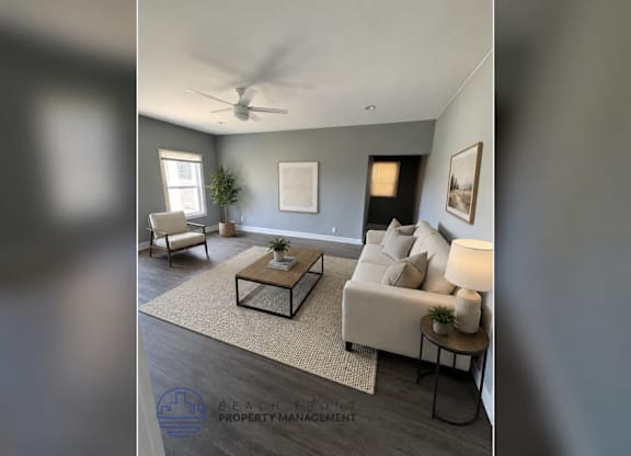 A living room with a white couch, a coffee table, and a ceiling fan.