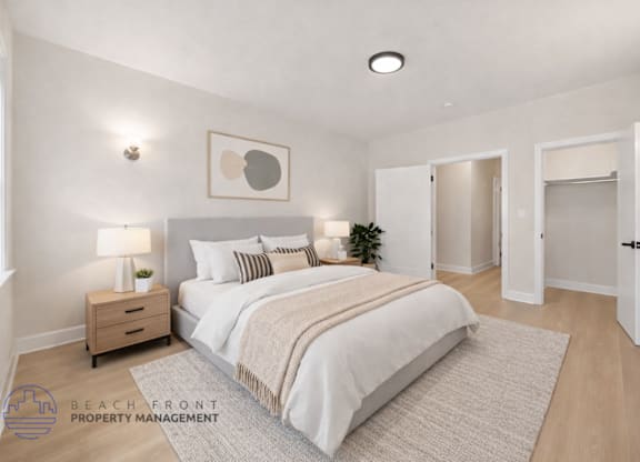 A well-lit bedroom with a large bed and a nightstand with a lamp.