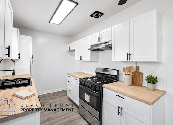 A kitchen with white cabinets and a wooden countertop.