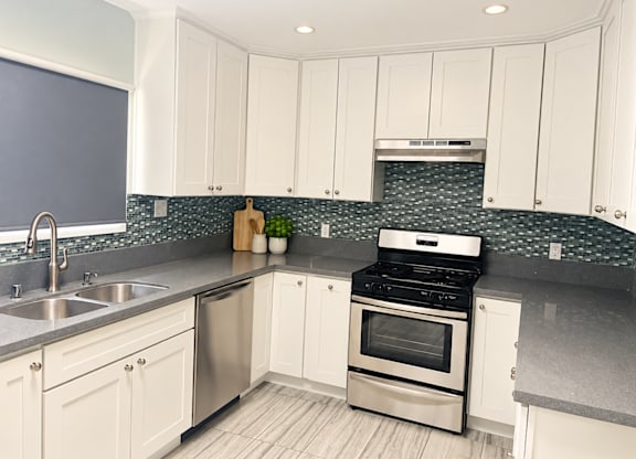 A kitchen with white cabinets and a stainless steel sink.