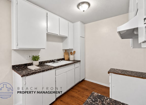 A kitchen with white cabinets and a granite countertop.