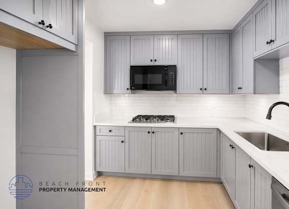 A kitchen with grey cabinets and a white countertop.