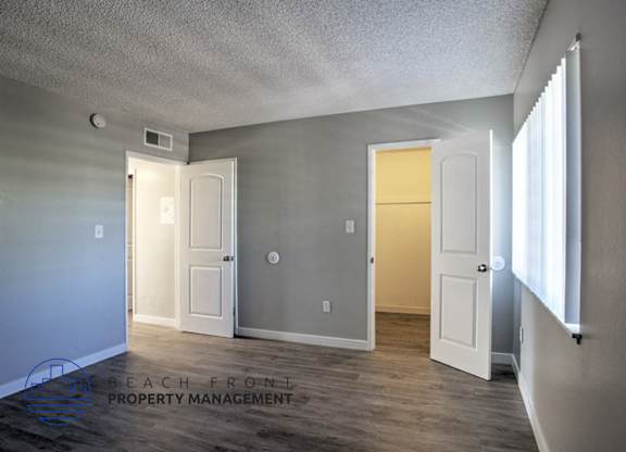 A room with a white door and a window on the right side.