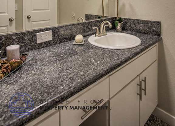 A bathroom with a granite countertop and a white sink.