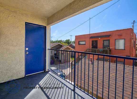 A balcony with a blue door and a black railing.