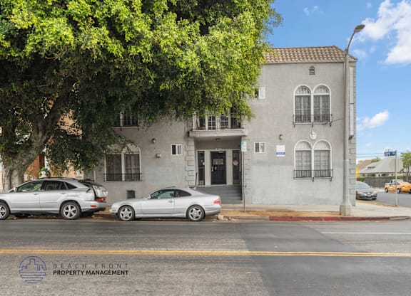 A street view of a building with cars parked in front.