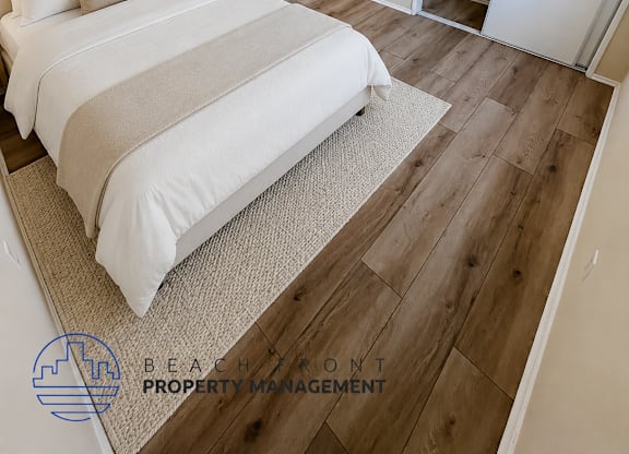 A bedroom with a large bed and a wooden floor.