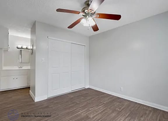 A room with a ceiling fan and a white door.