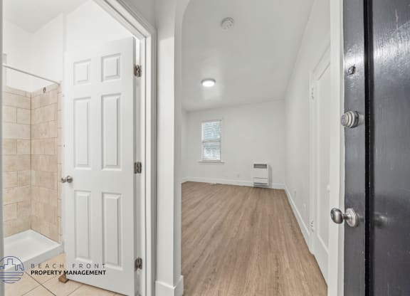 A room with a white door and a black door with a window in between.